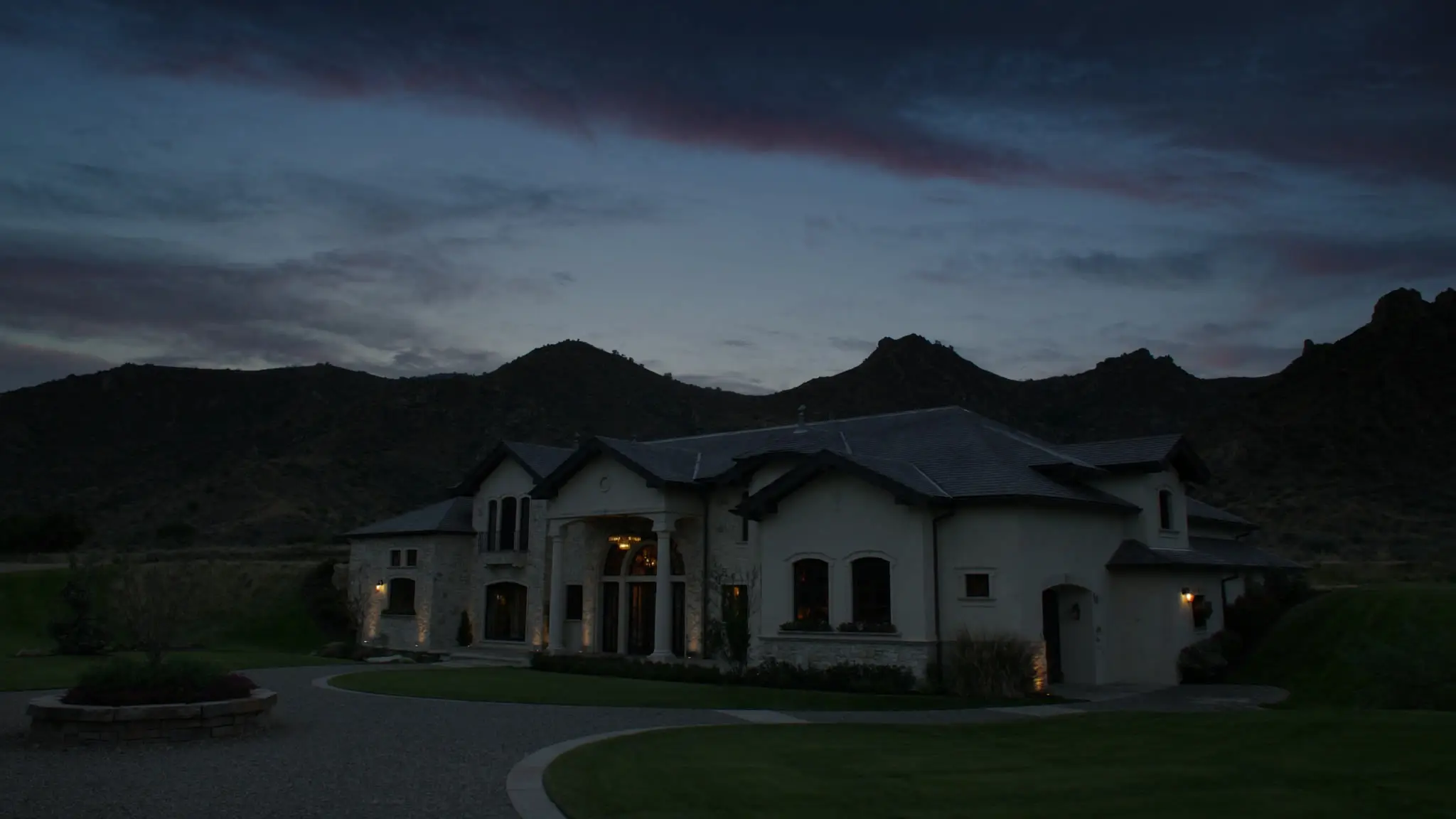 Columned Chatsworth home at twilight beneath the area's rocky sandstone ridgeline