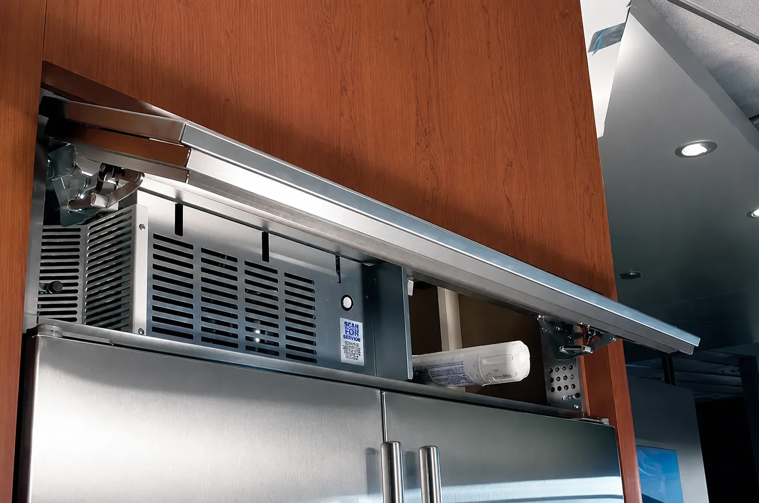 Technician inspecting the condenser area of a refrigerator