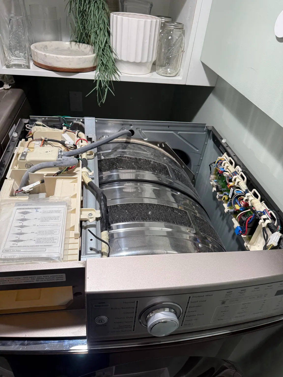 Top down view inside an open dryer chassis showing the drum and wiring harness