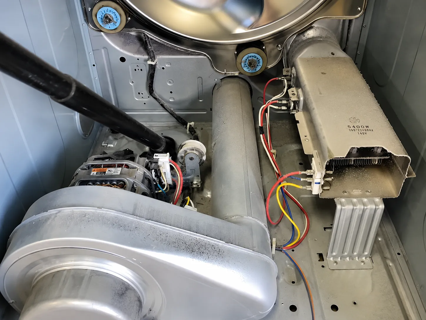 Inside a dryer cabinet — blower housing, drive motor, and the heating element assembly