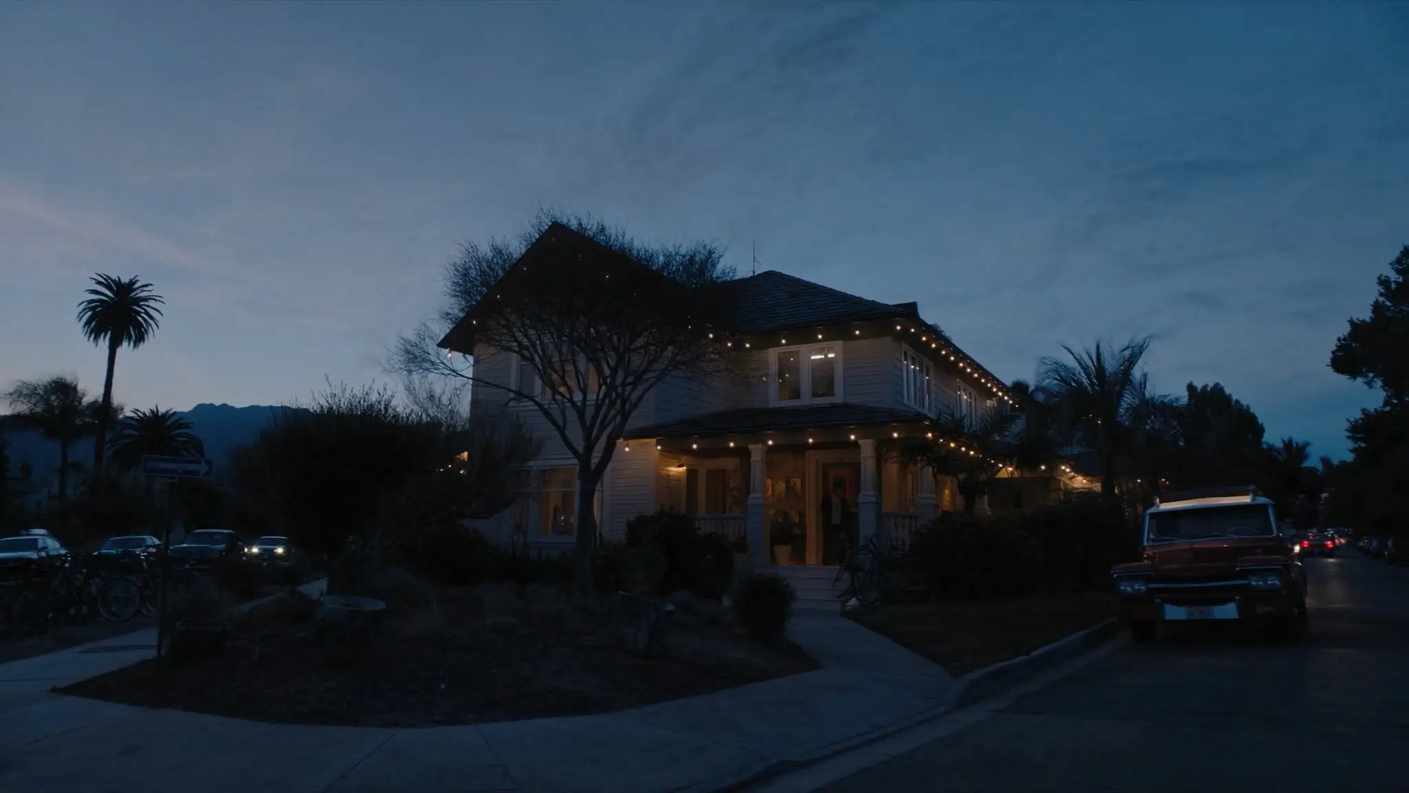 Two-story El Segundo home with porch string lights and palms at dusk
