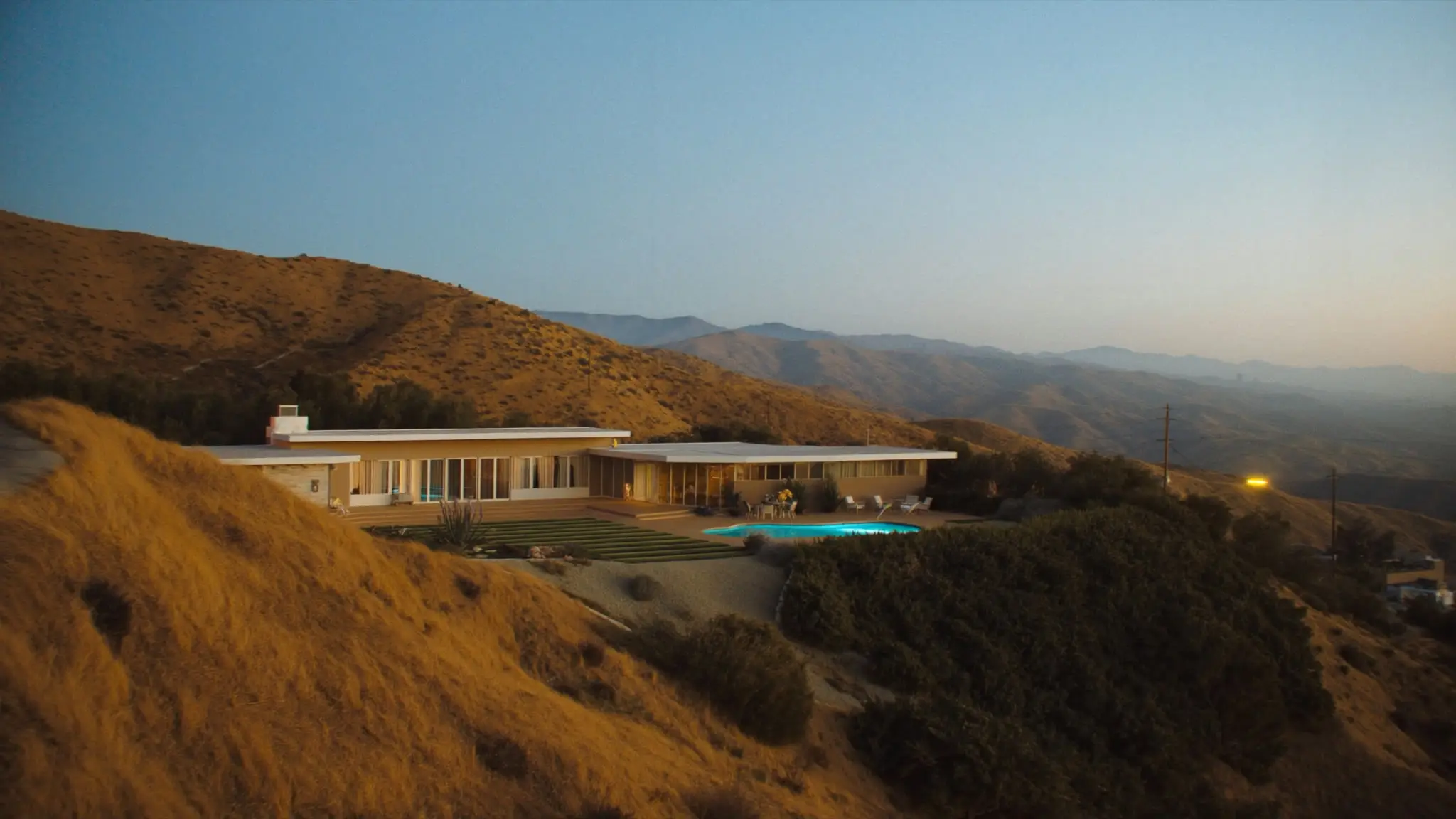 Mid-century Granada Hills home with a turquoise pool on a golden hillside at dusk