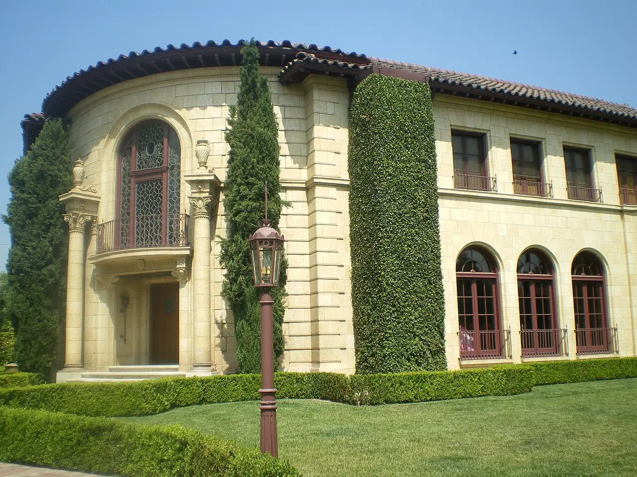 Grand stone mansion with arched windows and manicured hedges in Hancock Park