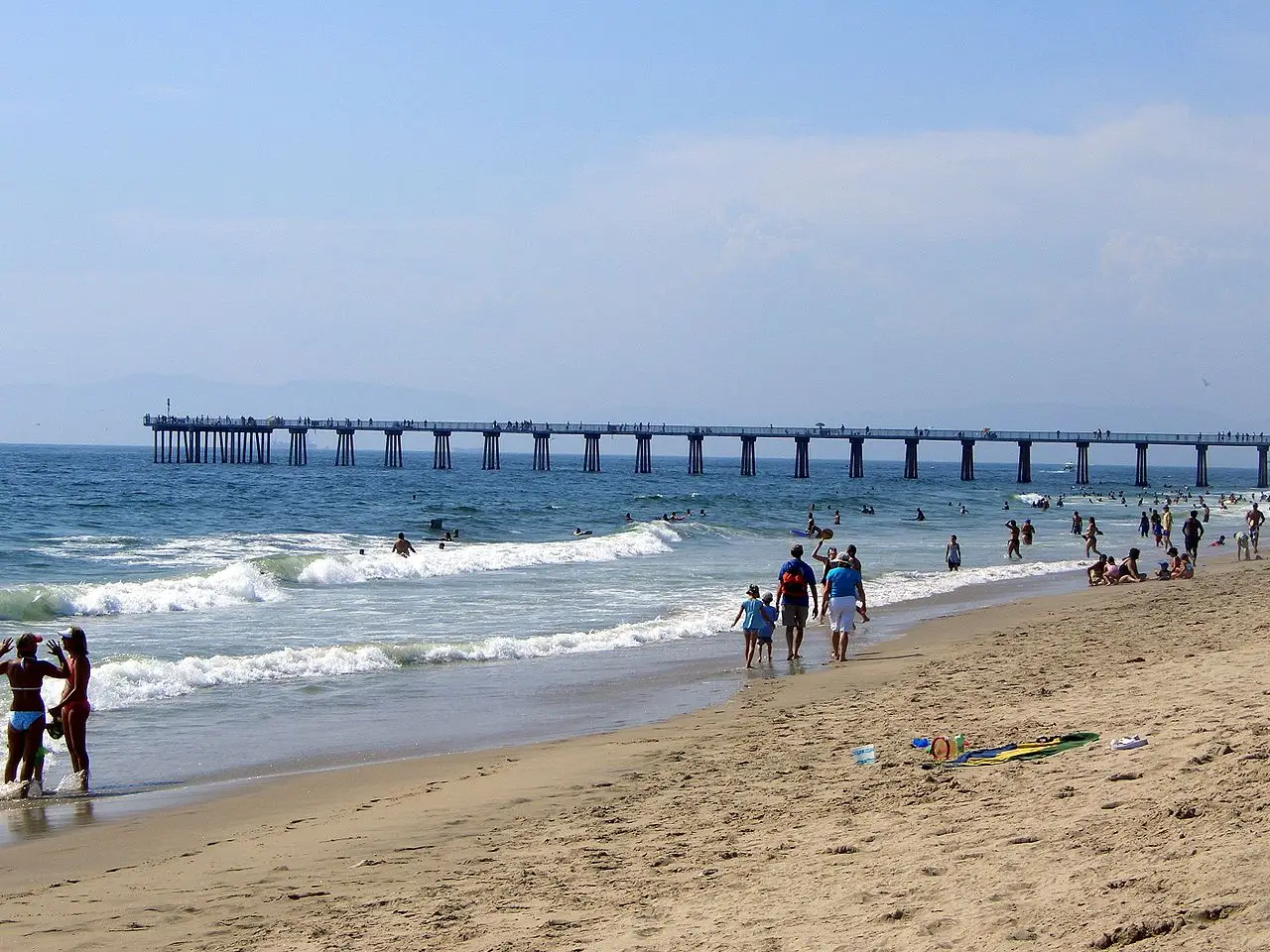 The Hermosa Beach pier stretching over the Pacific above a busy stretch of sand
