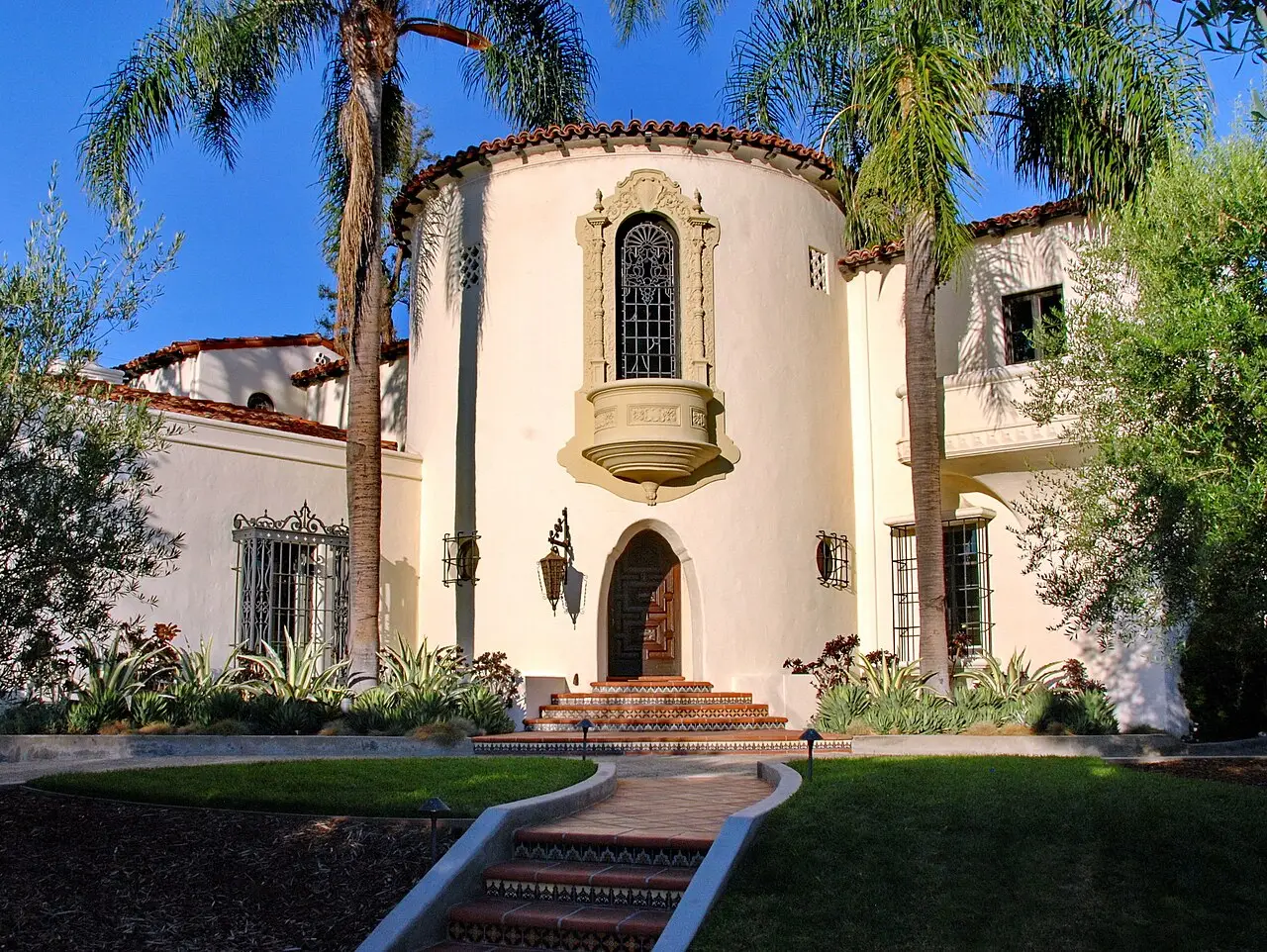 Spanish Revival home with a round turret, tiled steps, and palms in Los Feliz