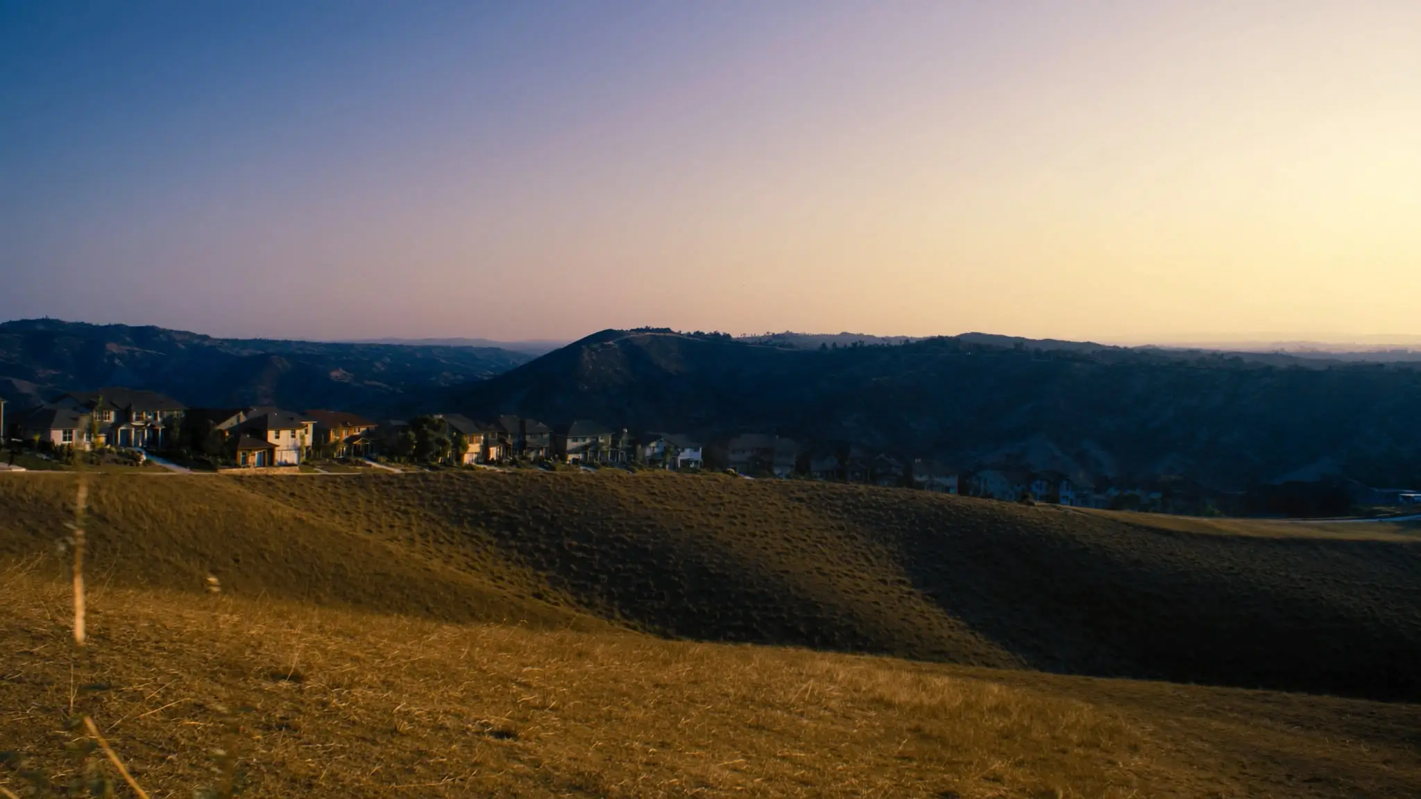 Row of two-story Moorpark homes along a golden grassy hilltop at dusk