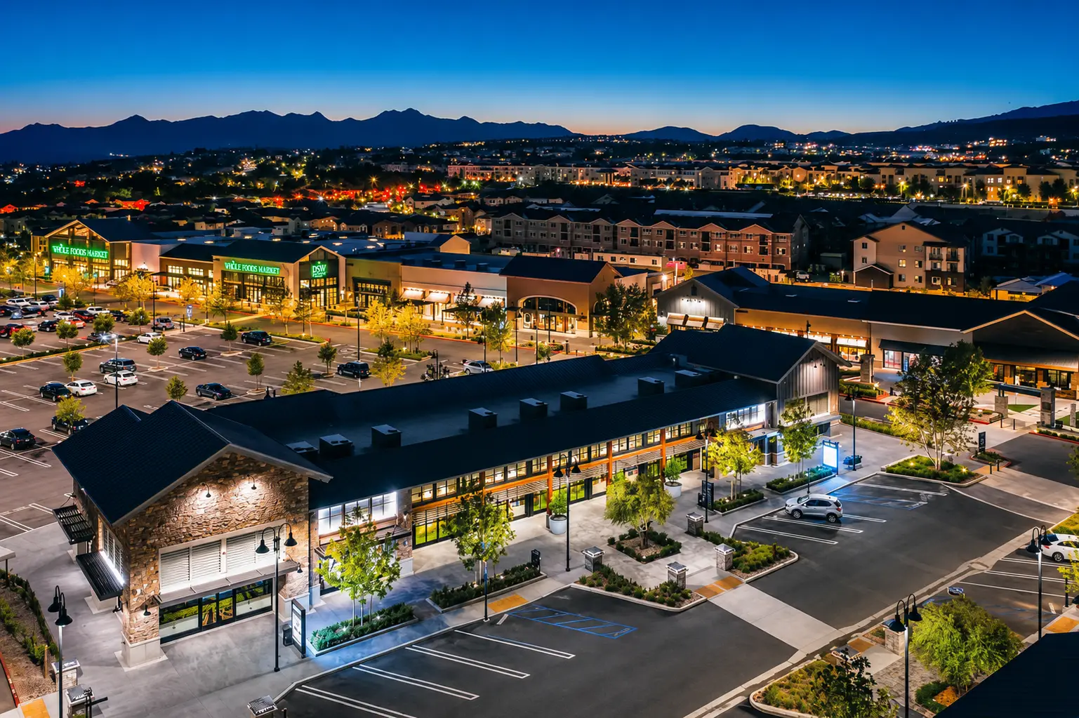 An open-air shopping center at dusk in Porter Ranch, storefronts lit beneath the Santa Susana Mountains