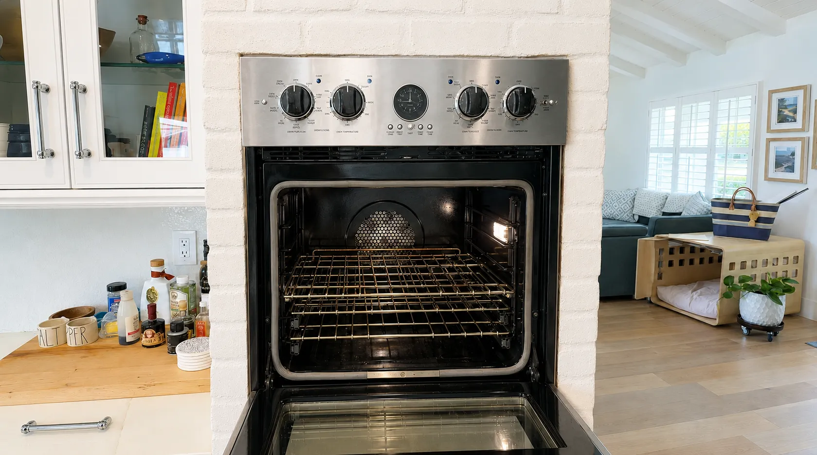 An open wall oven set in a white brick surround, control fascia and racks in view
